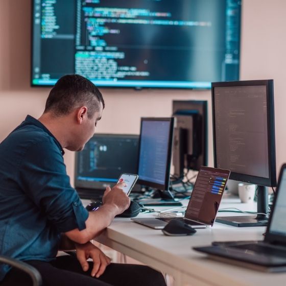 a software engineer sitting at a desk with several computers