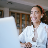 South American woman smiling and waving at a laptop screen while on a webinar