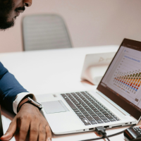 male accountant studying bar charts on laptop
