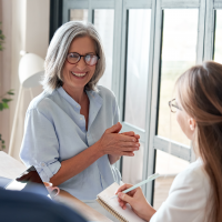 A smiling female older mentor interacting with co-workers in an office
