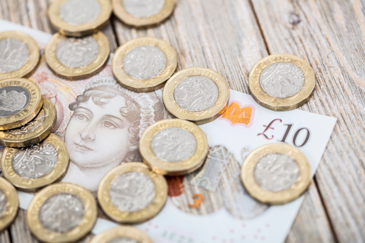 A group of pound coins on a £10 note