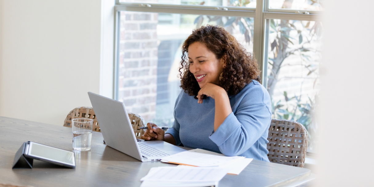 Smiling lady dressed in a blue jumper while in a virtual meeting while working from home
