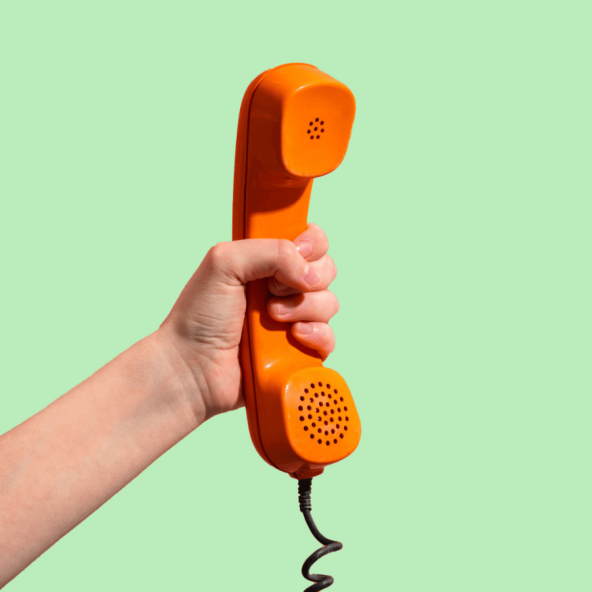 a hand holding a coral-coloured rotary phone handset