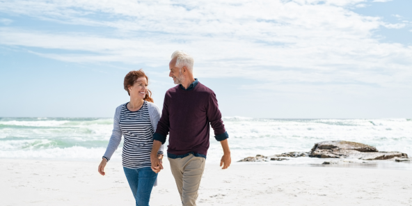 mature retired couple walking on the beach