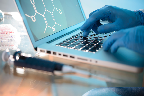 A closeup of a scientist using a laptop during a clinical trial