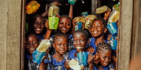 A group of smiling children holding packets of food in colourful containers