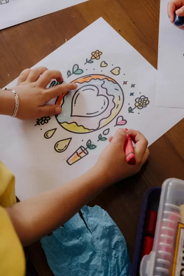 A child colouring in a drawing of a globe with a heart